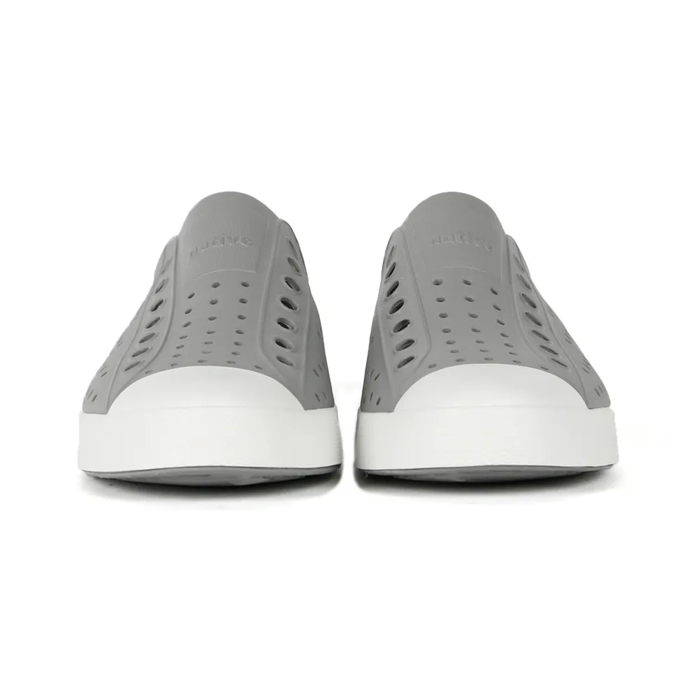 Native รองเท้า Jefferson Pigeon Grey ที่ถ่ายจากด้านหน้า แสดงให้เห็นรองเท้าสีเทาอ่อนแบบมีรูระบายอากาศและพื้นรองเท้าสีขาว เหมาะสำหรับใส่สบายๆ และกันน้ำได้ดี