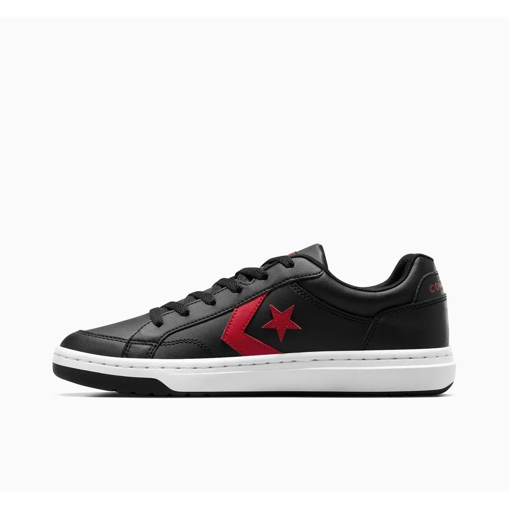 รองเท้า Converse Pro Blaze V2 สีดำตัดกับโลโก้ดาวและเชฟรอนสีแดงโดดเด่น วางด้านข้างบนพื้นหลังสีขาว พื้นรองเท้าด้านล่างมีสีขาวและดำ และมีคำว่า "CONVERSE" อยู่ที่ด้านข้างของพื้นรองเท้า