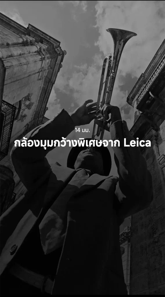 ชายใส่หมวกเป่าแตรในมุมมองต่ำ ท่ามกลางตึกเก่าสไตล์ยุโรป ภาพขาวดำ