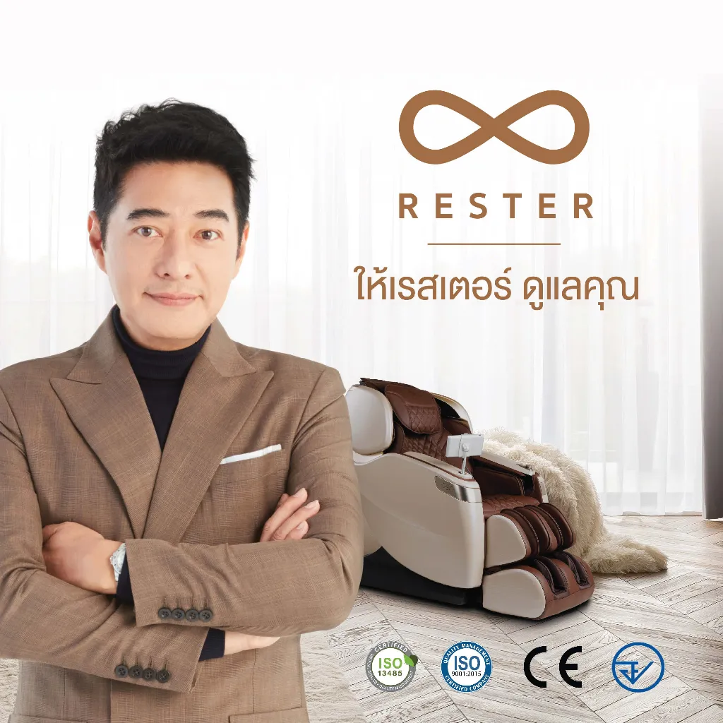 ก้อง สหรัถ ใส่สูทยืนกอดอกด้านหน้าเก้าอี้ผ่อนคลายสีครีมน้ำตาลในห้องนั่งเล่นสว่าง